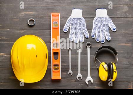 HardHat mit Baumaterial auf dunklem Holzhintergrund Stockfoto