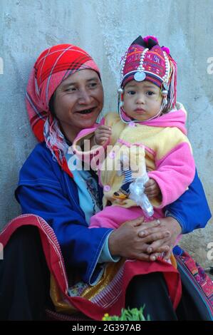 Eine ältere Frau aus der ethnischen Akha Hill Gemeinde sitzt mit ihrer Enkelin auf dem Morgenmarkt in Doi Mae Salong in Chiangmai, Thailand. 15. Dezember 2007. Stockfoto