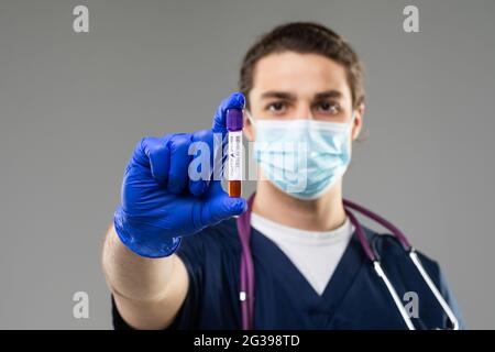 Ein junger Wissenschaftler untersucht einen Bluttest auf Coronavirus. Diagnose 2019-ncov. Positives Bluttestergebnis für Kovid 19. Kaukasischer Arzt mit a B. Stockfoto