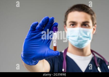 Coronavirus pandemia. Die Epidemie des chinesischen Coronavirus Menschen in einem Schutzanzug untersucht das Virus in einer Röhre isoliert auf grauem Hintergrund Stockfoto