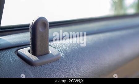 Schließen Sie die Verriegelungstaste an der Innentür des Fahrzeugs. Taste für die Türverriegelung im Innenraum des Fahrzeugs in Nahaufnahme Stockfoto