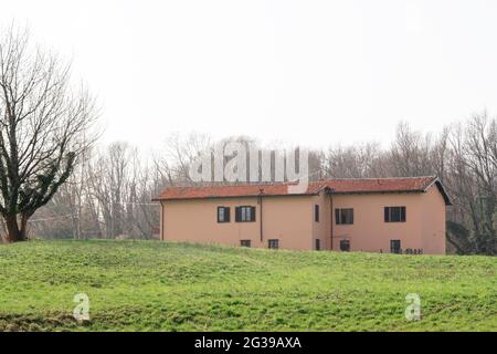 Haus auf grünen Wiese Feld Hügel im späten Frühjahr. Stockfoto