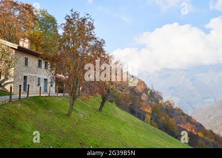 Blick auf das Haus auf der Bergseite, malerische Alpen Herbstlandschaft, Berghügel in der Lombardei, Italien. Touristenabenteuer Stockfoto