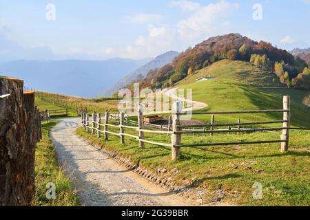 Malerische Alpen Herbstlandschaft, Holzzaun und Berghügel in der Lombardei, Italien. Touristenabenteuer Stockfoto