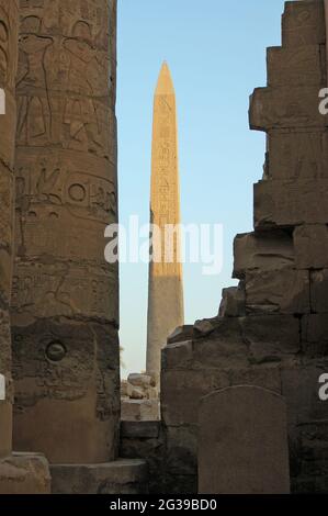 Ein altägyptischer Obelisk aus Stein, der den goldenen Sonnenschein auf den Ruinen des Tempels von Karnak in Luxor, Ägypten, fängt. Stockfoto