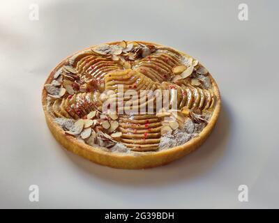 Runde Birne- und Mandeltarte mit rosa Pfeffer auf weißem Font Stockfoto