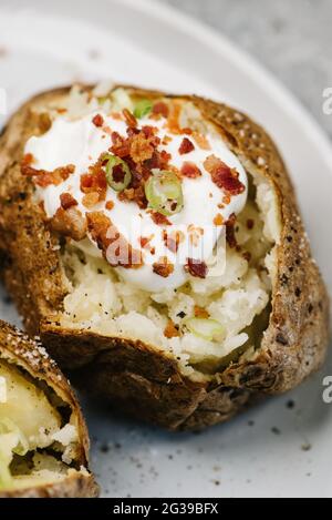 Nahaufnahme der gebackenen Kartoffel mit Sauerrahm und Speck Stockfoto