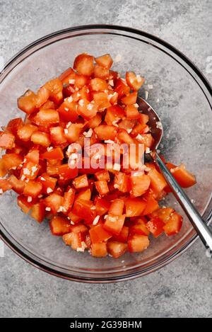 Gewürfelte Tomaten und Knoblauch in einer Glasschüssel Stockfoto