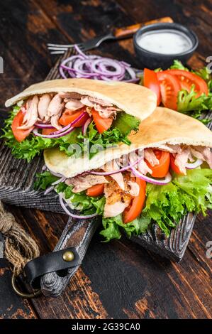 Griechische Gyros in Pita-Brot mit Gemüse und Sauce eingewickelt. Dunkler Holzhintergrund. Draufsicht Stockfoto