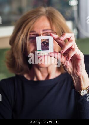 CREMO, ITALIEN - 11. Jun 2021: Ältere elegante kaukasische blonde Frau mit 35-mm-Dia, die sie emotional berührt Stockfoto