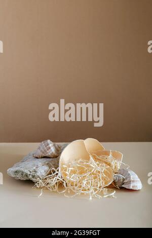 Leeres Podium auf kraftbraunem Papierhintergrund. Leeres Standdisplay Mockup auf beigem Hintergrund aus Muschelsteinen und Eierschale für die Kosmetik Stockfoto