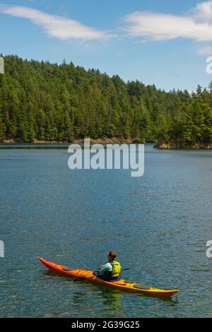 Eine Frau fährt mit dem Kajak auf dem Mountain Lake im Moran State Park auf der Orcas Island, San Juan Islands im US-Bundesstaat Washington. Stockfoto