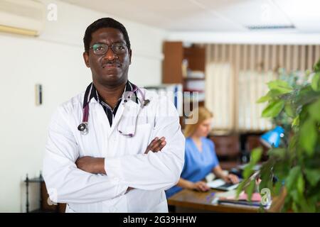 Professioneller afroamerikanischer Arzt, der im medizinischen Büro steht Stockfoto