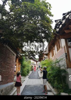 SEOUL, KOREA, SÜD - 29. Jun 2019: Touristen fotografieren im Dorf Bukchon Hanok, Bäume und traditionelle Häuser. Seoul, Südkorea, 29. Juni 2019. Stockfoto