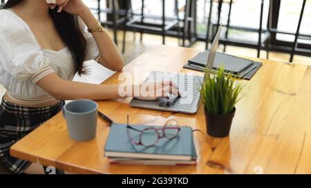 Eine kurze Aufnahme einer Teenagerin, die mit einem Laptop und Büchern auf einem Holztisch Hausaufgaben machte Stockfoto