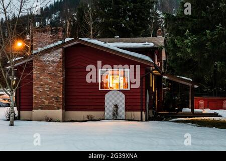 REVELSTOKE, KANADA - 14. MÄRZ 2021: Privathaus und Straßenansicht in Kleinstadt Abendzeit früher Frühling mit Schnee Stockfoto