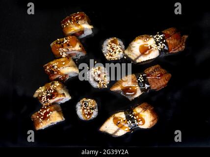 Gebackene Brötchen und Sushi auf schwarzem Hintergrund von oben Stockfoto