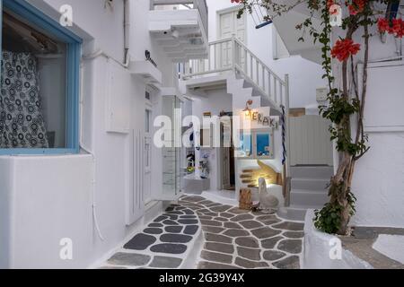 Mykonos, Kykladen, Griechenland. 20.Mai 2021. Chora Street. Geschenke Shop griechische Kunst, leere enge gepflasterte Gasse, weiß getünchte Häuser, blaue Fenster Stockfoto