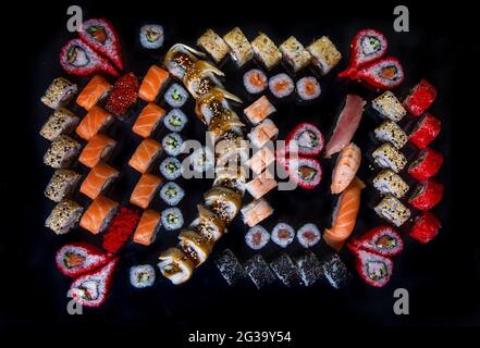 Großes Set mit Sushi und Rollen japanischer Küche, Draufsicht auf schwarzem Hintergrund. Stockfoto