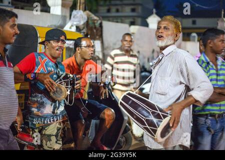 Der indische Musiker spielt Bongos mit Auto-Rikscha-Treibern (aufgenommen mit f/1.8 Kamerablende mit enger Schärfentiefe), Agonda, Goa, Indien Stockfoto