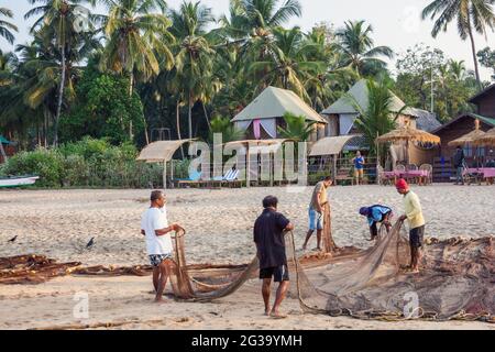 Indische Fischer, die am Strand, Agonda, Goa, Indien, zu ihren Fischernetzen tendieren Stockfoto