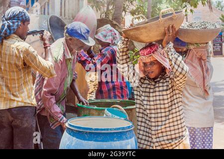 Indische Arbeiterinnen, die schwere Lasten auf ihren Köpfen auf der Baustelle in Agonda, Goa, Indien, tragen Stockfoto