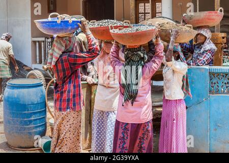 Indische Arbeiterinnen, die schwere Lasten auf ihren Köpfen auf der Baustelle in Agonda, Goa, Indien, tragen Stockfoto