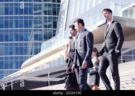 Gruppe erfolgreicher Geschäftsleute, die draußen die Treppe hinunter laufen Stockfoto