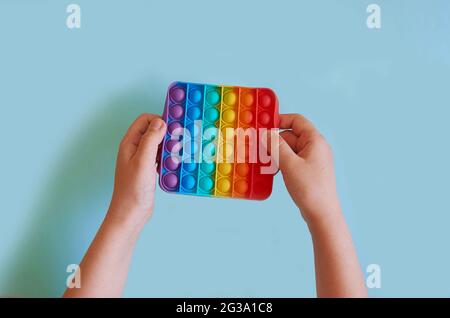 Kinderhände halten Silikon buntes Spielzeug Pop IT Stockfoto