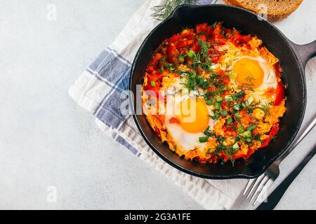 Traditionelles israelisches Gericht. Eier mit Tomaten. Shakshouka in einer Pfanne auf einem hellen Tisch servieren. Draufsicht, Kopierbereich Stockfoto