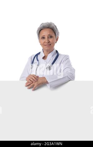 Reife asiatische Arzt hält leere Banner isoliert auf weißem Hintergrund Stockfoto