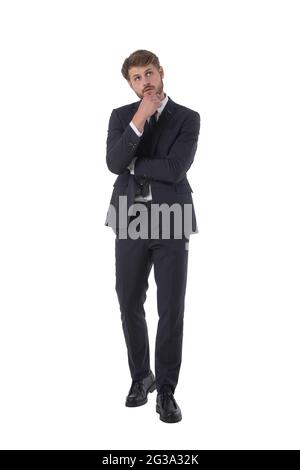 In voller Länge Porträt von nachdenklichen Geschäftsmann nach oben halten Hand zum Kinn Studio isoliert auf weißem Hintergrund, Geschäftsleute Stockfoto