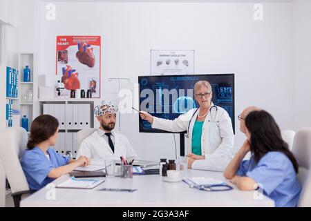 Das medizinische Team des Krankenhauses forscht an der Gehirnaktivität mithilfe von Headsets mit Sensoren, die die Erfahrung in der Radiographie überwachen. Ärzte, die die Behandlung von Krankheiten analysieren, arbeiten im Konferenzsaal Stockfoto