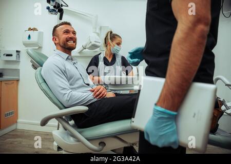 Lächelnder kaukasischer männlicher Kunde glücklich nach erfolgreicher Zahnreinigung Stockfoto