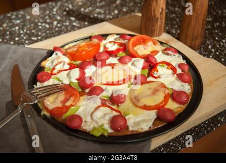 Rührei mit Würstchen, Tomaten, Pfeffer und Grünpflanzen in der Pfanne Stockfoto