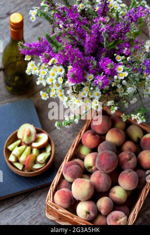 Frische Pfirsiche Früchte im Korb auf dunklem Holz rustikalen Hintergrund, Draufsicht. Sommerernte der Früchte. Stillleben. Eine Gruppe von reifen Pfirsich. Flach liegend vegan Stockfoto