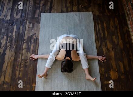 Junge attraktive Frau in Baddha Konasana Pose gegen Boden gewinnen Stockfoto