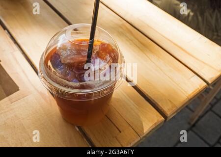 Kaffee in Plastikglas auf Holztisch mitnehmen Stockfoto