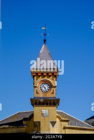 Staycation Idee. Eastbourne Railway Station Uhrenturm, mit Wappen, gegen einen wolkenlosen blauen Himmel. East Sussex, England, Großbritannien Stockfoto