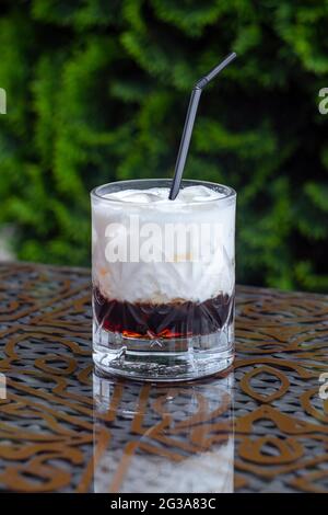 Weißer russischer Cocktail mit Stroh, alkoholisches Mixgetränk, alkoholisches Getränk auf dem Tisch im Restaurant, Cocktail mit Kaffeelikör und Eis in einem Glas Stockfoto