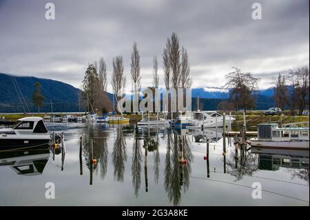 Te Anau Marina, Fiordland, Neuseeland. Ruhige Szene, Freizeitboote, die auf einem See mit Reflexionen in ruhigem Wasser festgemacht sind Stockfoto