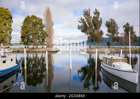 Te Anau Marina, Fiordland, Neuseeland. Ruhige Szene, Freizeitboote, die auf einem See mit Reflexionen in ruhigem Wasser festgemacht sind Stockfoto