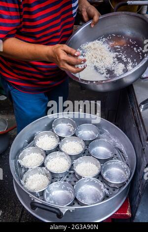 Ein thailändischer Straßenverkäufer bereitet Reis zu, um zu einem beliebten Favoriten gekocht zu werden - klebriger Reis. Stockfoto