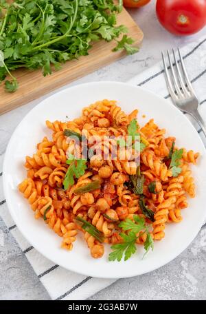 Fussilli-Pasta mit Kichererbsen in Tomatensauce und Parmesan. Gesundes veganes Essen. Vertikale Aufnahme Stockfoto