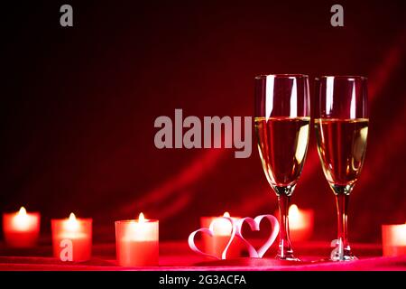 Valentinstag-Feier, Gläser Champagner, Kerzen und Herzen auf roter Seide Stockfoto