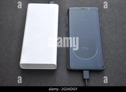 Foto eines schwarzen Smartphone mit Powerbank zum Aufladen mit schwarzem Hintergrund verbunden Stockfoto