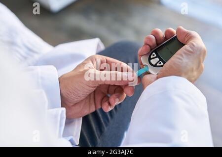 Die Teststreifen im Blutzuckermessgerät werden von Hand zur Messung des Blutzuckerspiegels überprüft Stockfoto