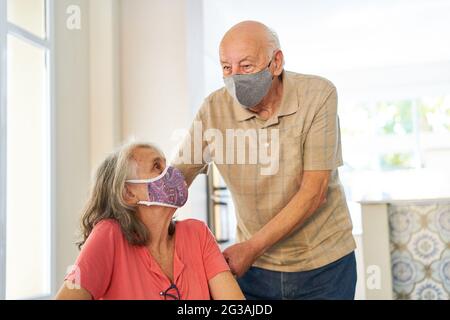 Seniorenpaar mit Gesichtsmaske wegen Covid-19 und Coronavirus als Symbol für gefährdete Gruppe Stockfoto
