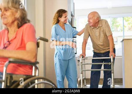 Zufriedene Pflegekraft, die sich in einem Pflegeheim um ältere Menschen sorgt Stockfoto