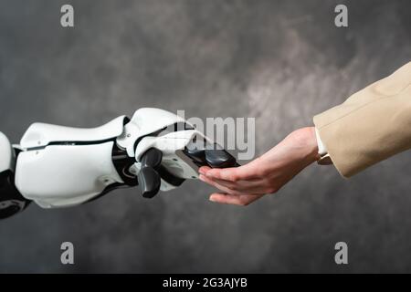 Beschnittene Ansicht einer Geschäftsfrau, die die Hand eines humanoiden Roboters berührt Stockfoto